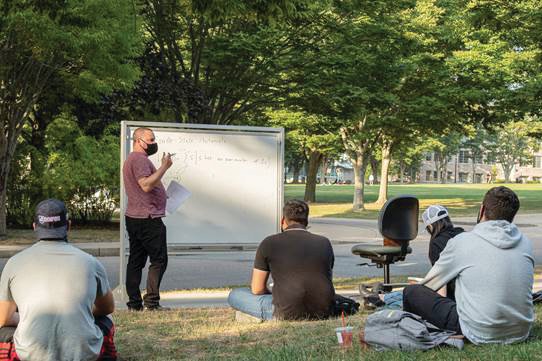 Assistant Professor of Computer Science Noah Daniels uses a whiteboard to teach his class during a mild day in fall 2020 during the height of the pandemic